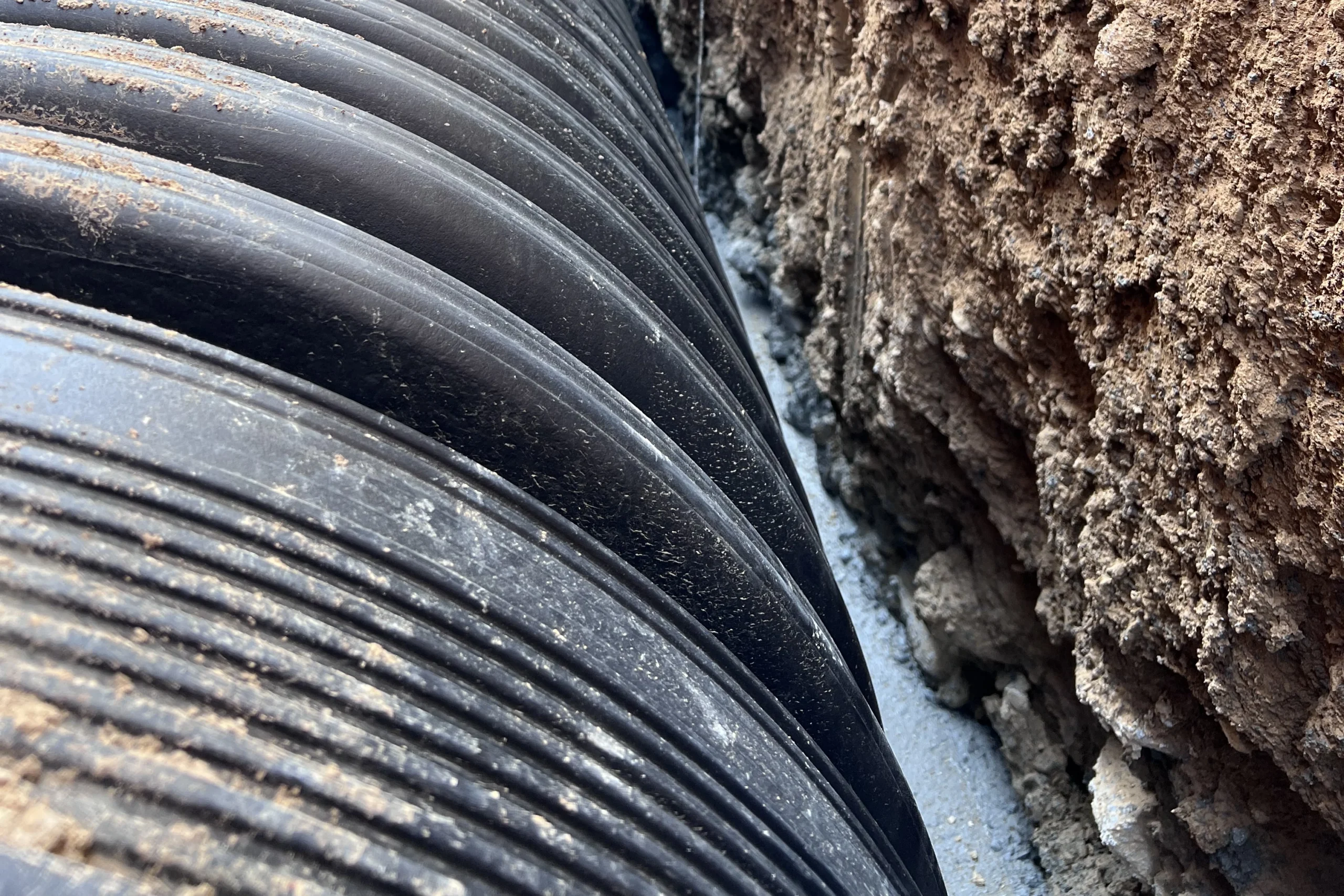 HDPE pipe compaction with mechanical equipment over the backfill in an open trench